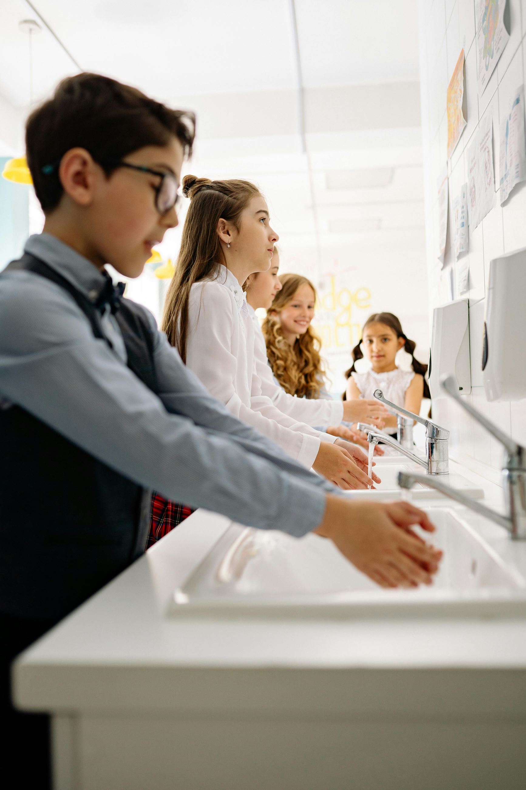 Children washing hands at sink faucets